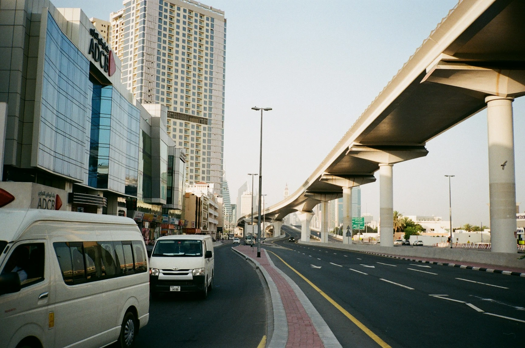 a white van driving down a street next to tall buildings in Dubai